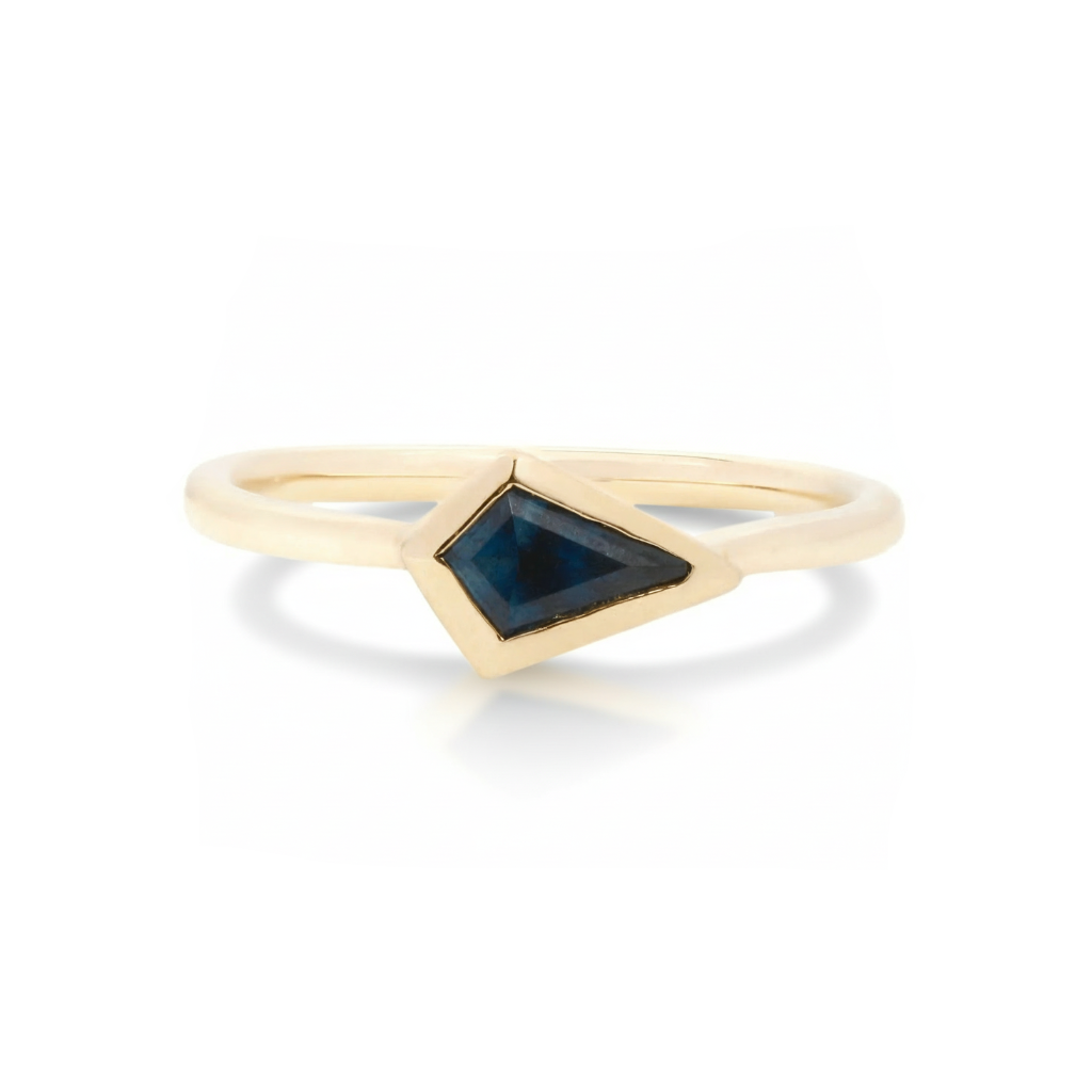 18k yellow gold ring with a kite-shaped deep blue sapphire on a white background.