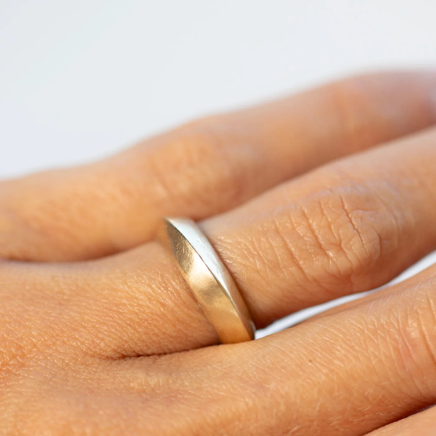 14k gold saucer ring worn on the hand showing its smooth sculptural design