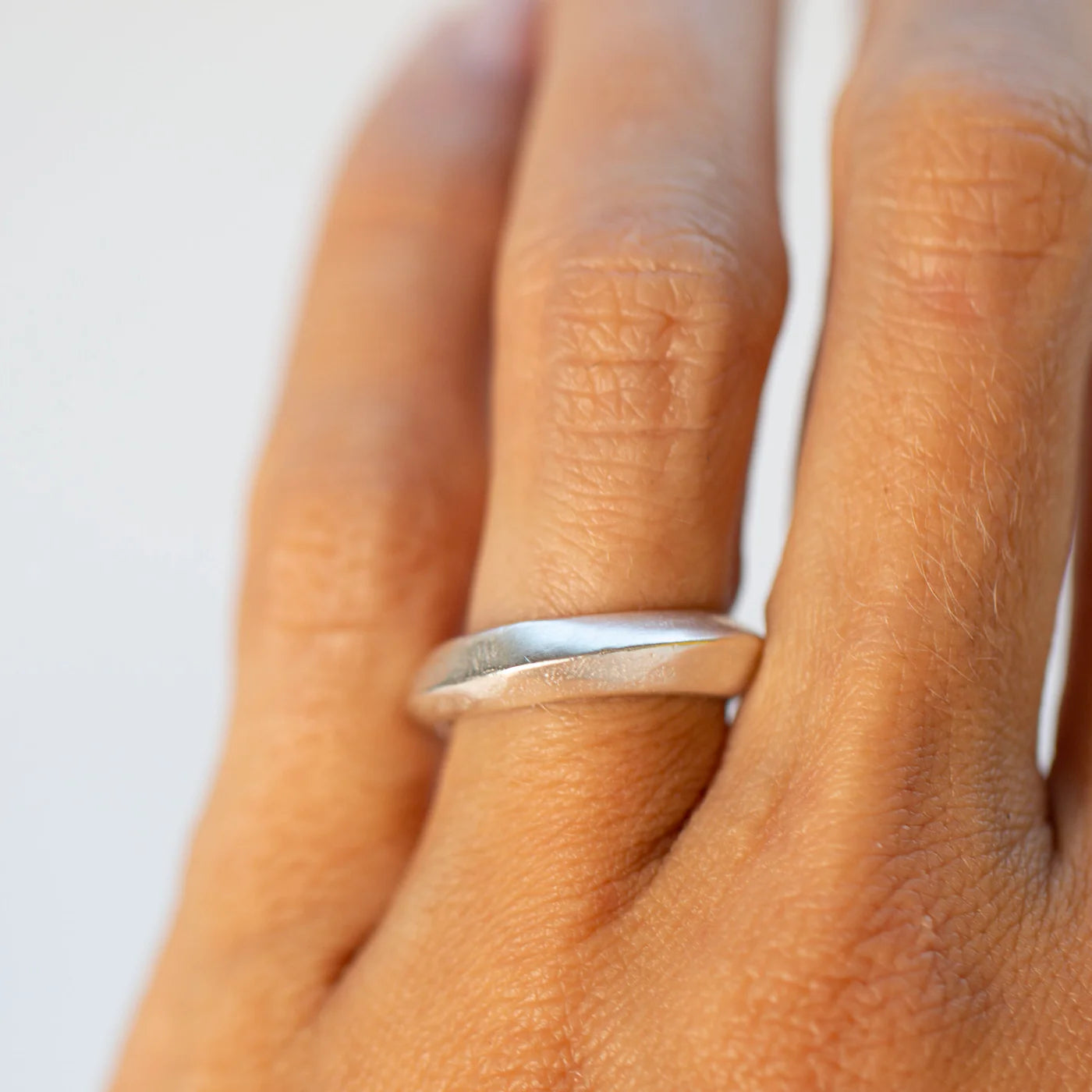 Sterling silver saucer ring worn on the hand highlighting its smooth curved shape