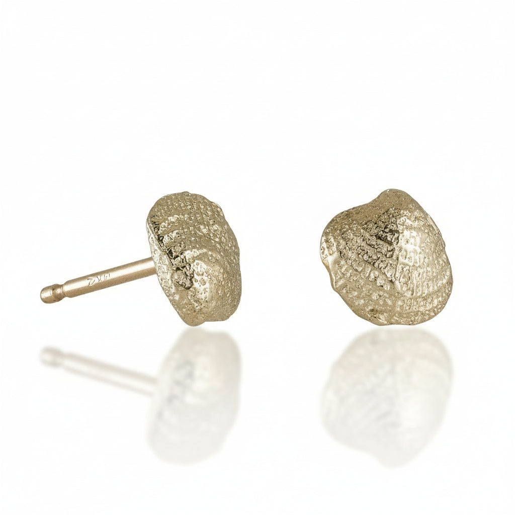 Hand-carved seashell stud earrings in solid 14k yellow gold by Alexis Pavlantos, featuring organic ocean-inspired textures and delicate sculptural details with friction post backs.