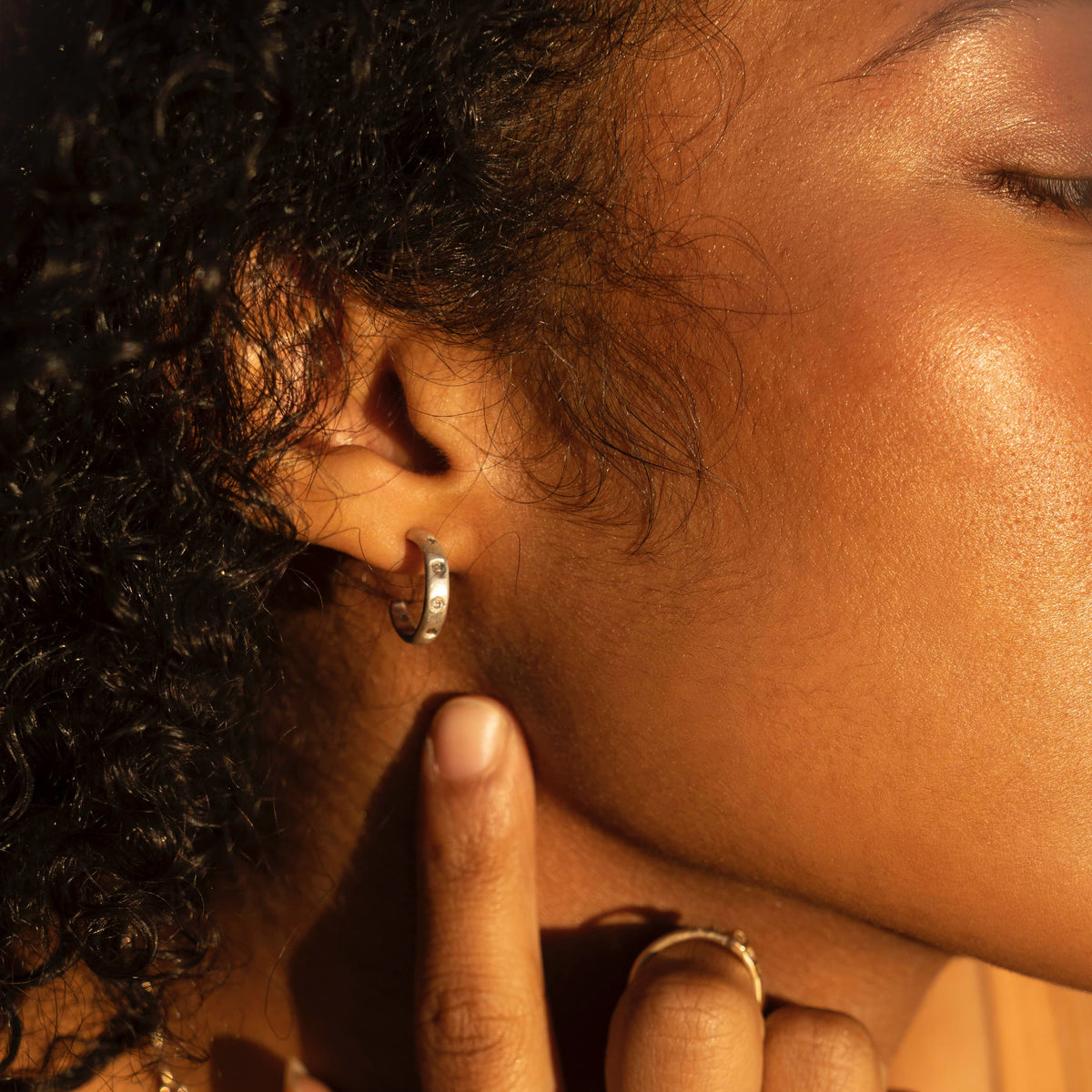 Close-up of a model wearing Sedimentary Sparkle Hoops in sterling silver with recycled diamonds and 14k yellow gold accents.