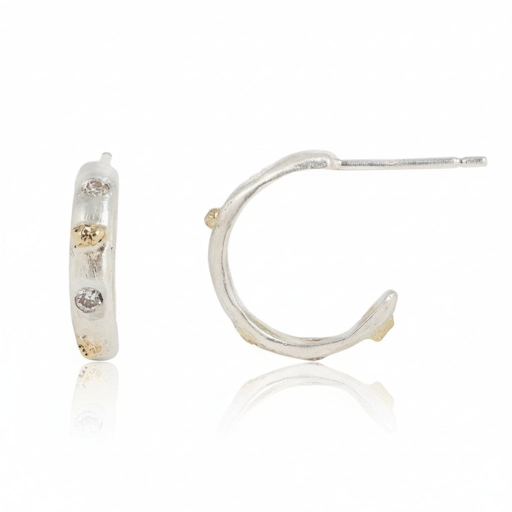 Side view of handcrafted sterling silver hoop earrings showing sculptural sediment-inspired texture, recycled diamond settings, and 14k yellow gold accents.