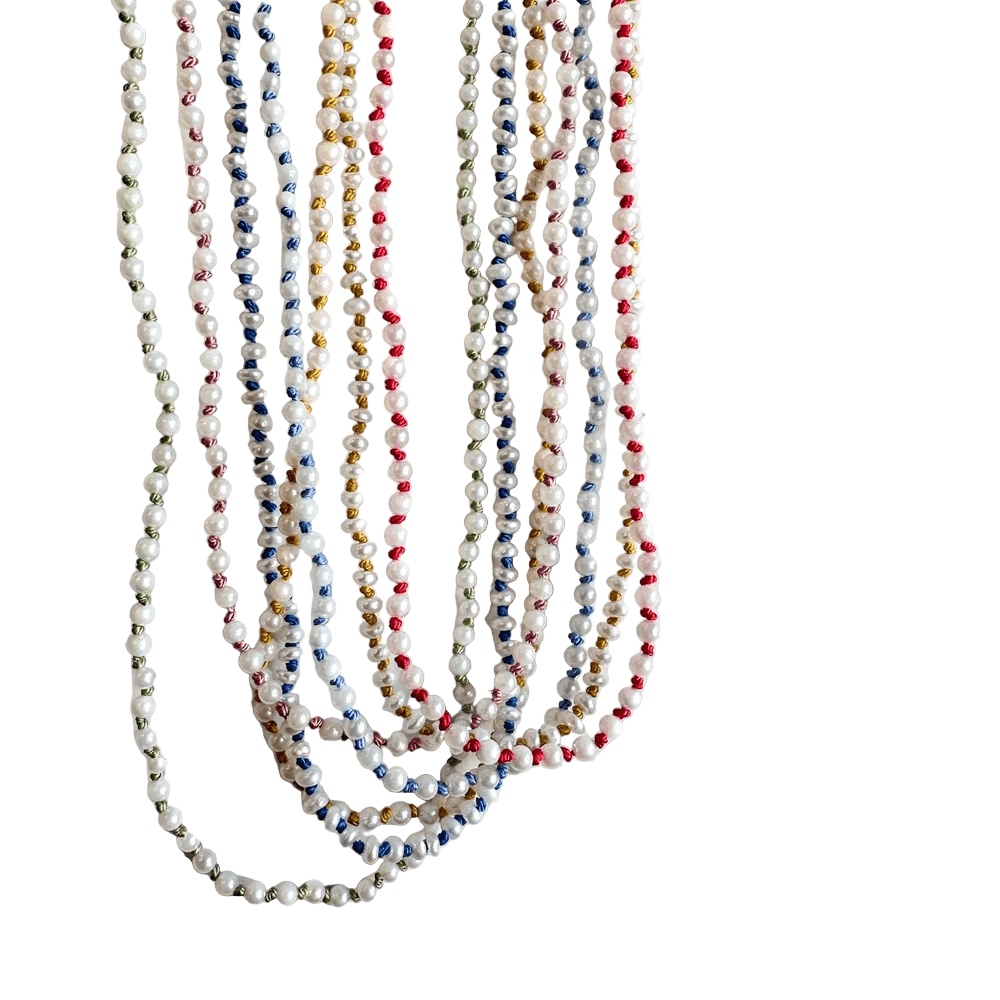 Close-up of multiple seed pearl necklaces hanging together in soft natural light.