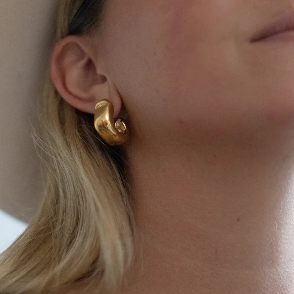Model wearing Serrano Hoops in 14k gold, close-up ear view showing sculptural design.