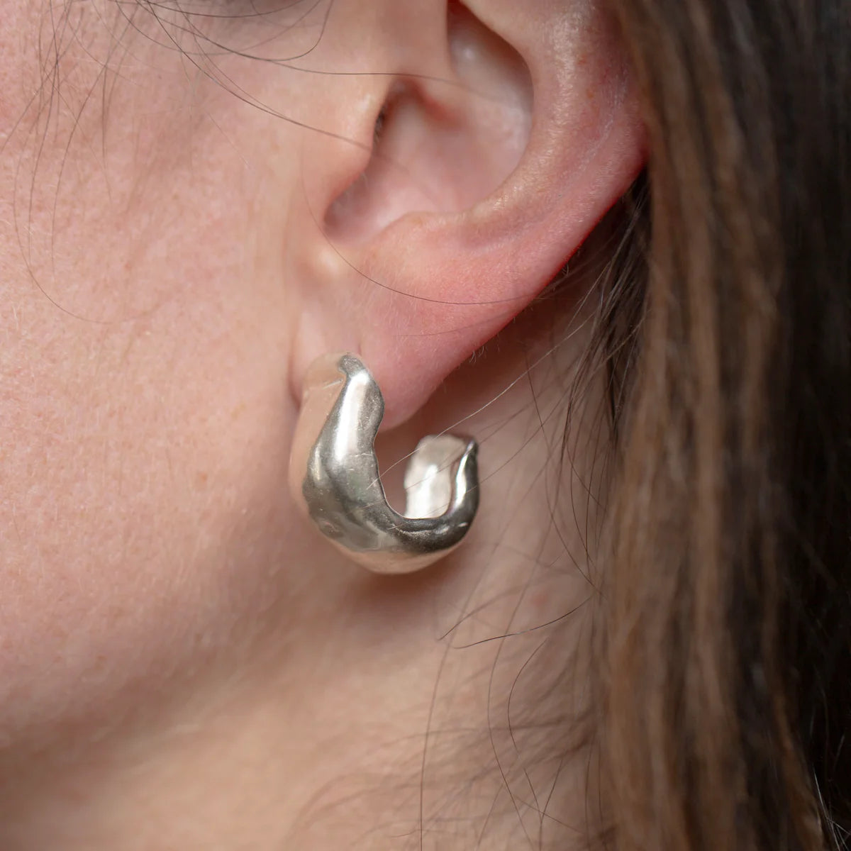 Close-up ear view of model wearing Serrano Hoops in sterling silver.