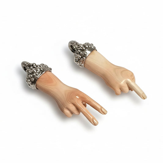 Two sculptural hand pendants by Shaya Durbin in recycled sterling silver with hand-carved shell, showing the middle finger and peace sign designs.