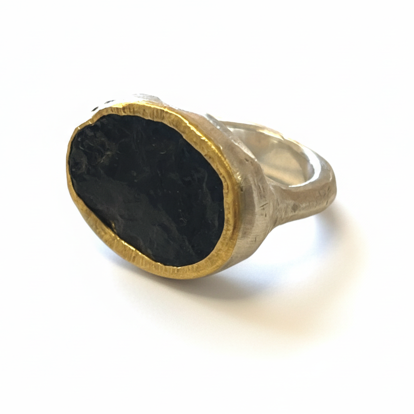 Angled view of Shaya Durbin's black tourmaline ring highlighting the rough natural gemstone, warm 22k yellow gold bezel and sculptural silver band.