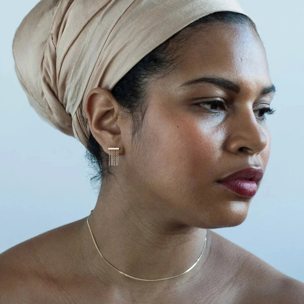 Side profile of a woman wearing a short 14k gold fringe earring.