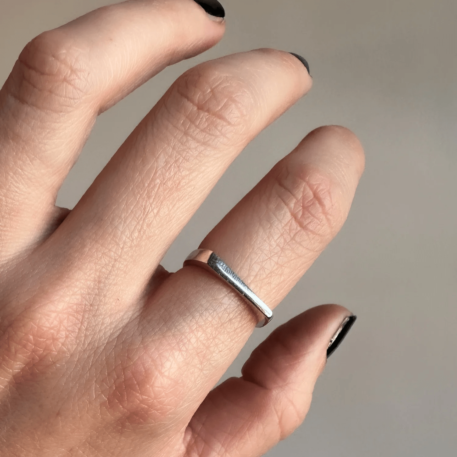 Sterling silver modern tapered band worn on a hand in natural indoor light.