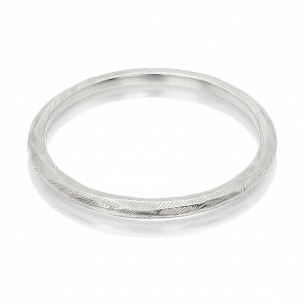 Angled view of the Reyes sterling silver bangle by Ladha Jewelry, showing its rounded shape and subtle carved texture.