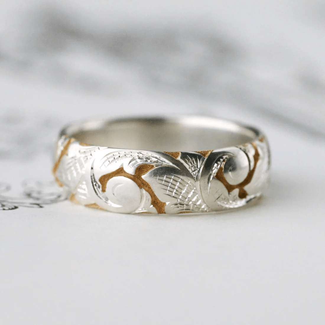 Two-tone slim acanthus band with engraved scroll and leaf motif – front view.