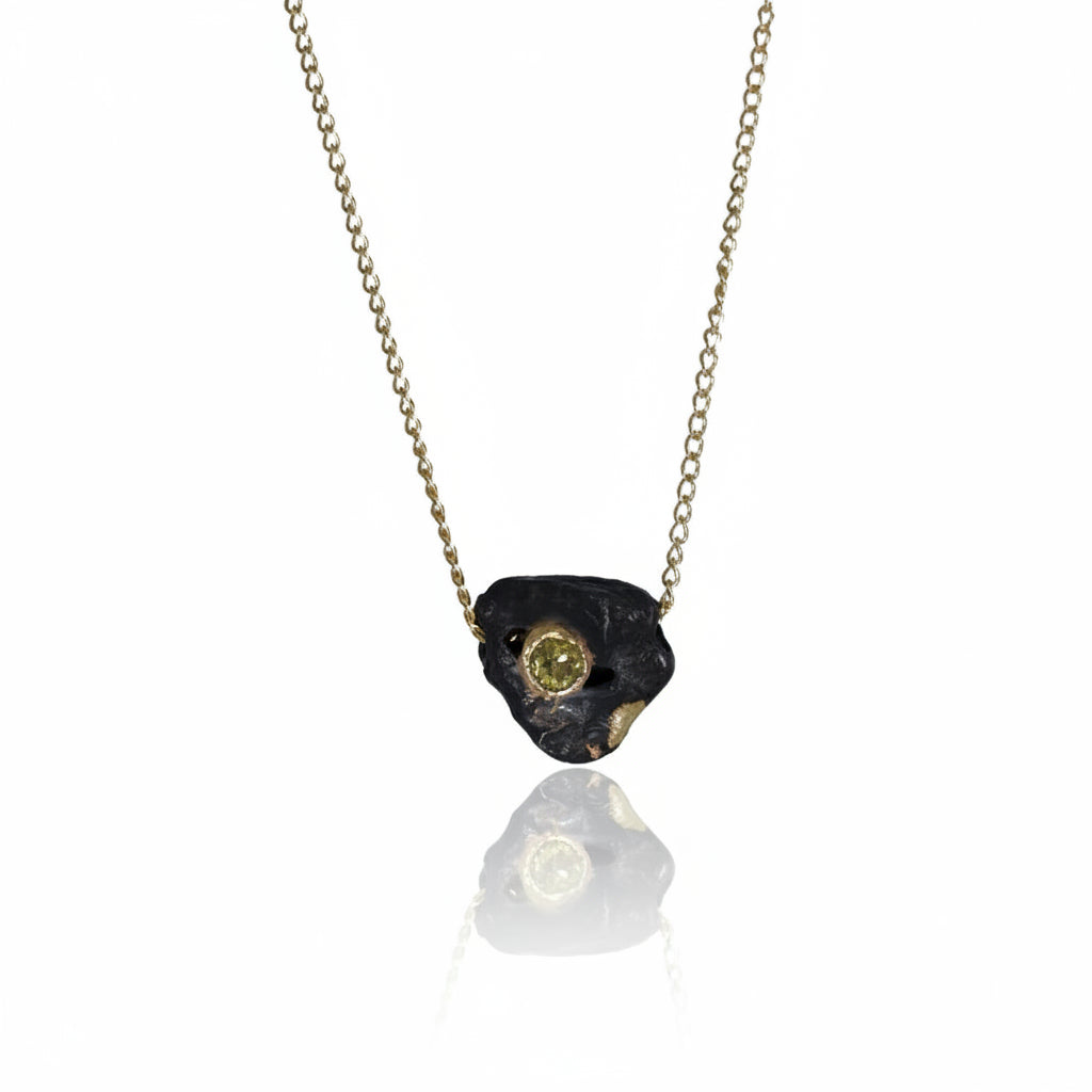 Hand-carved Small Rolling Rock Pendant by Alexis Pavlantos in oxidized sterling silver with recycled 14k yellow gold accents and a 4mm citrine marquise, suspended from a 16-inch gold chain.
