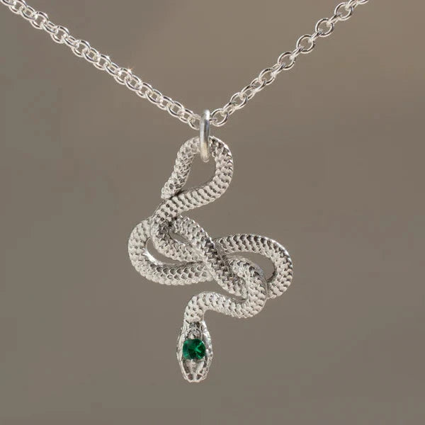 Close-up of the sterling silver Snake Guardian Necklace by Michaela Farkasovska, featuring a coiled serpent design with a small emerald at its tail.