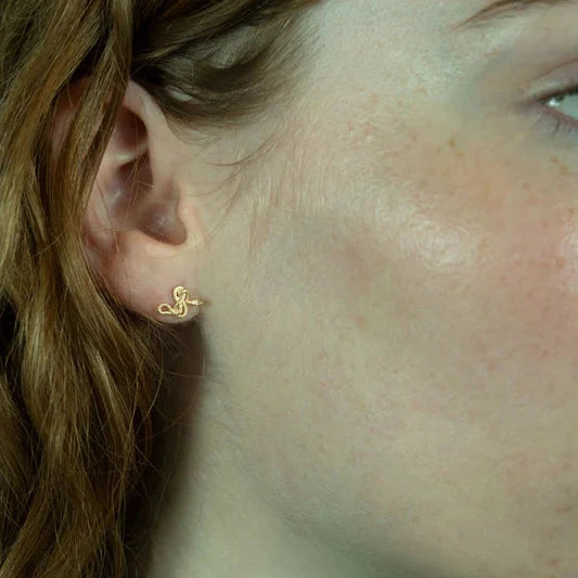 Snake Guardian Stud Earrings in 14k yellow gold worn on a model, showing their delicate size and sculptural design.