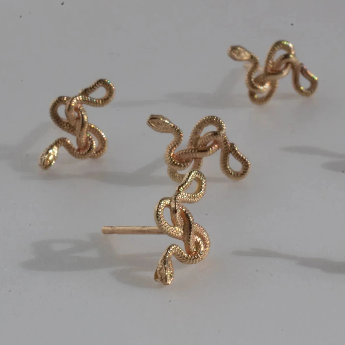 Detailed view of the Snake Guardian Stud Earrings by Michaela Farkasovska, showing the sculptural coiled snake forms in solid gold.