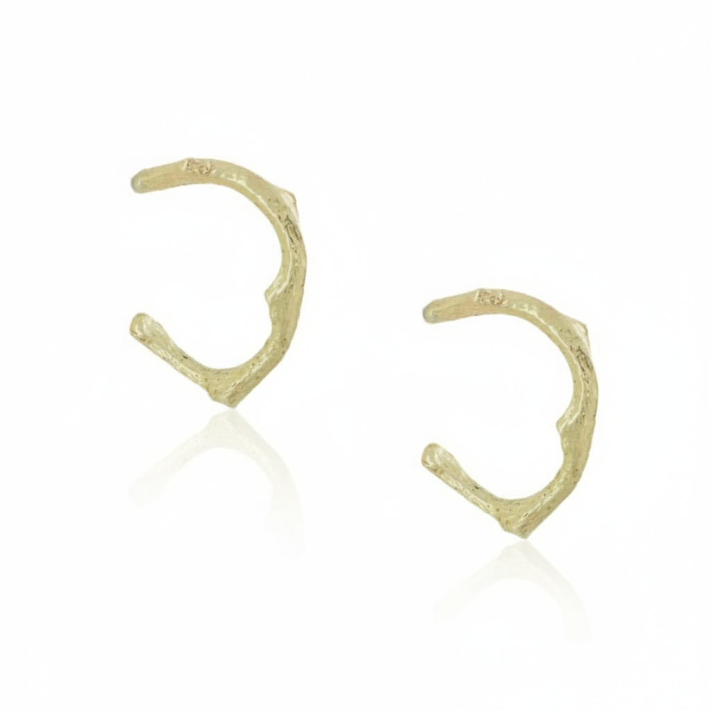 Pair of handcrafted 14k yellow gold Sprig Hug Hoop Earrings by Alexis Pavlantos, featuring delicate twig-inspired textures and a small sculptural huggie design.
