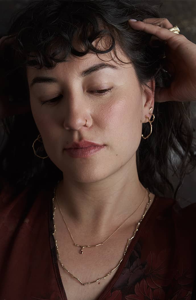 Portrait of a model wearing handcrafted Sprig Hug Hoop Earrings by Alexis Pavlantos, highlighting their delicate nature-inspired design and everyday styling.