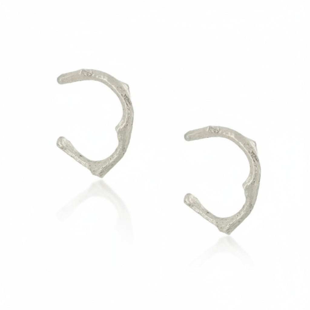 Sterling silver Sprig Hug Hoop Earrings featuring hand-carved branch-like textures, an organic open-hoop shape, and a delicate everyday design.