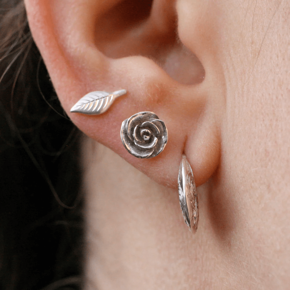 Sterling silver engraved leaf stud earring worn on the ear.
