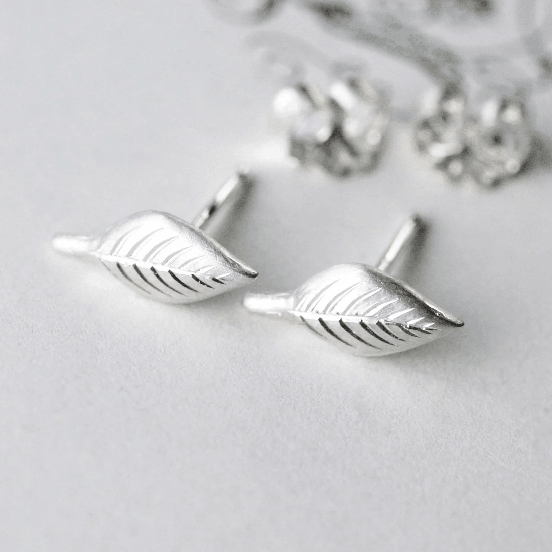 Close-up of sterling silver engraved leaf stud earrings showing detailed leaf engraving.