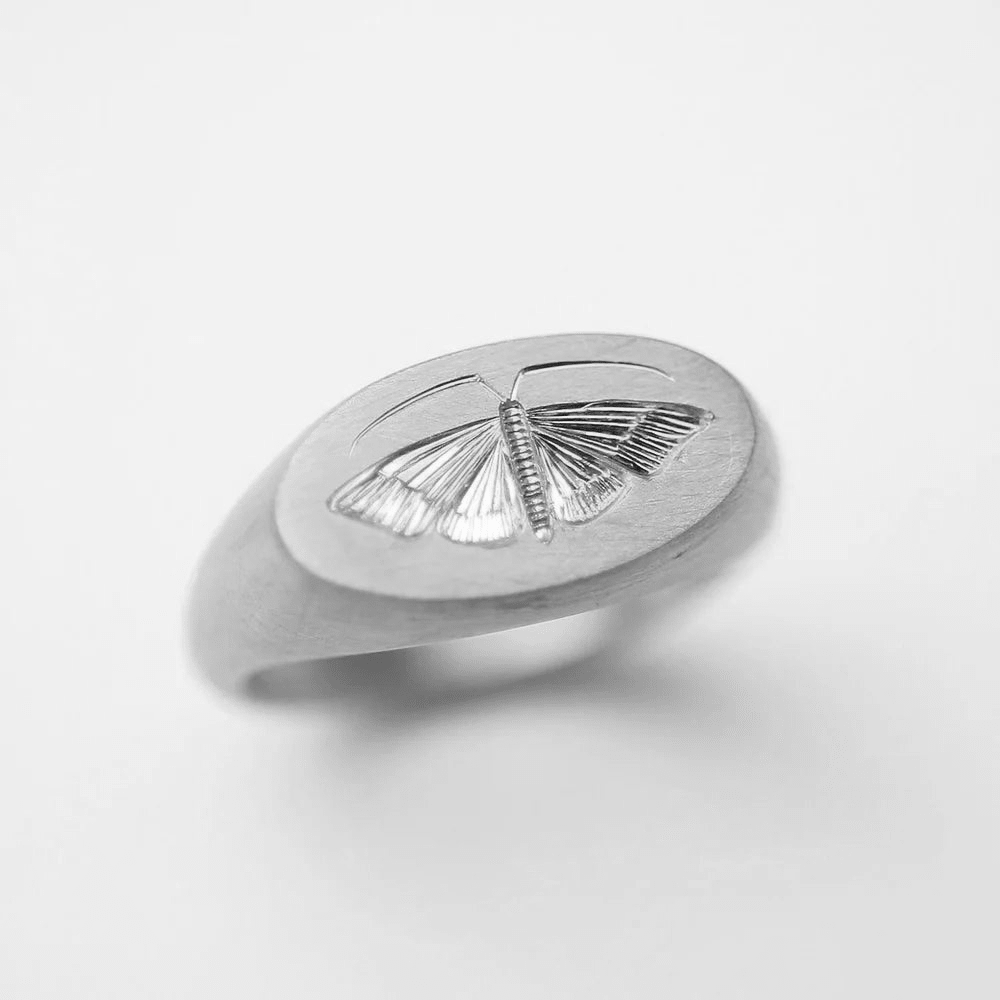 Front view of a sterling silver house moth ring with hand-engraved detailing.