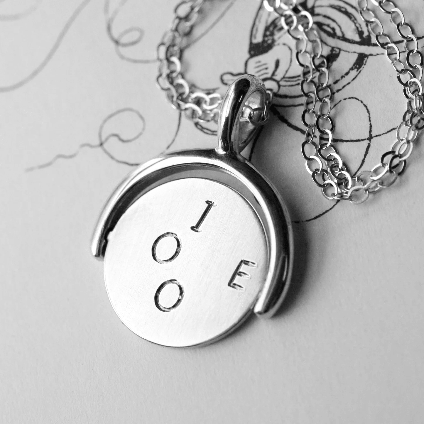 Sterling silver spinner pendant featuring the engraved I O E side.