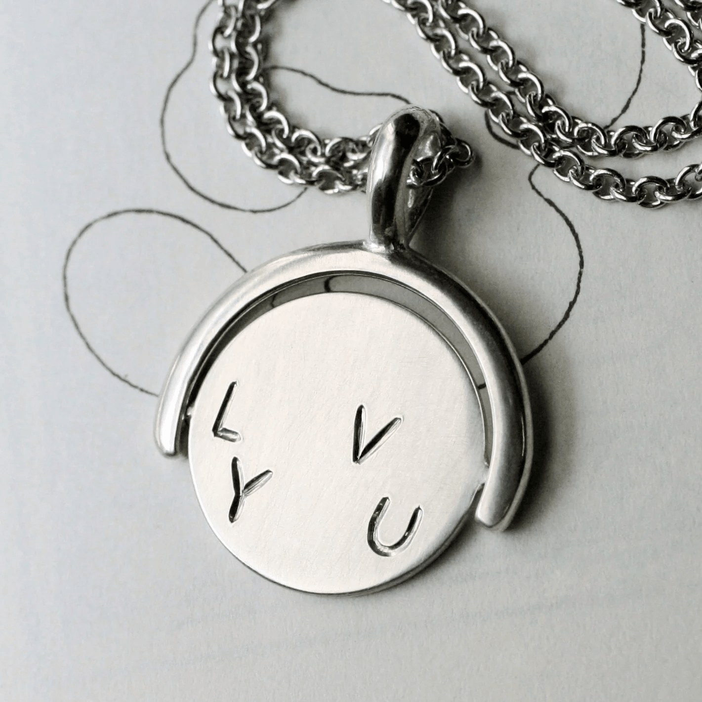 Sterling silver spinner pendant featuring the engraved L Y U side.