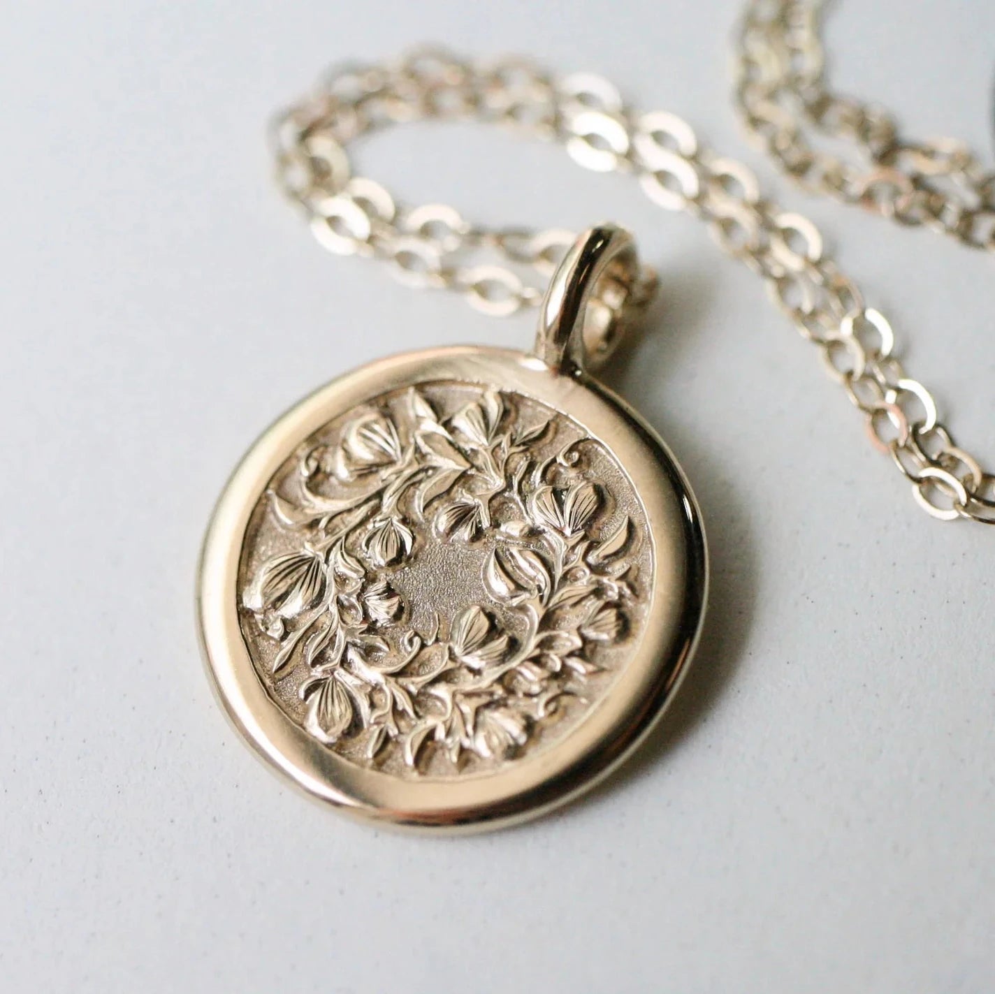 14k gold Sweet Pea pendant on chain – hand-engraved floral motif, front view.