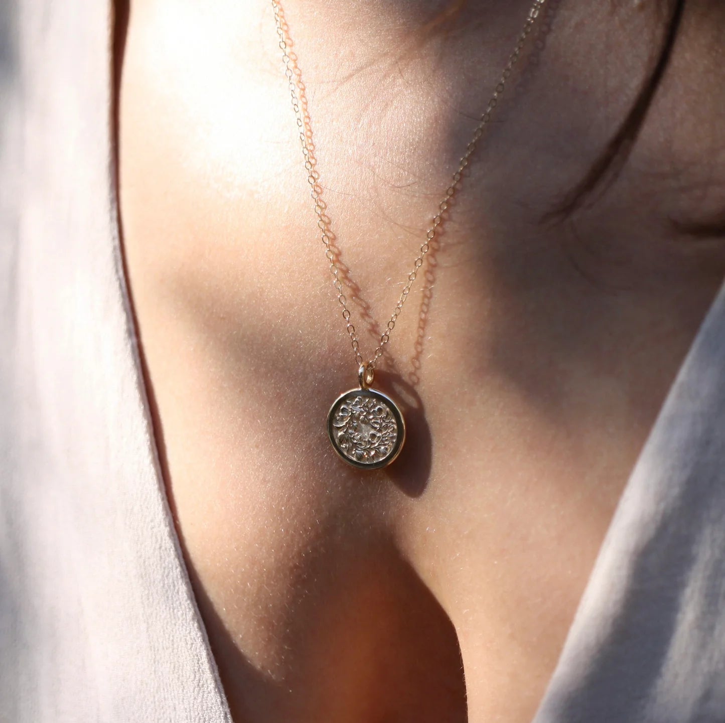 14k gold Sweet Pea engraved pendant worn on chest – delicate floral medallion necklace.