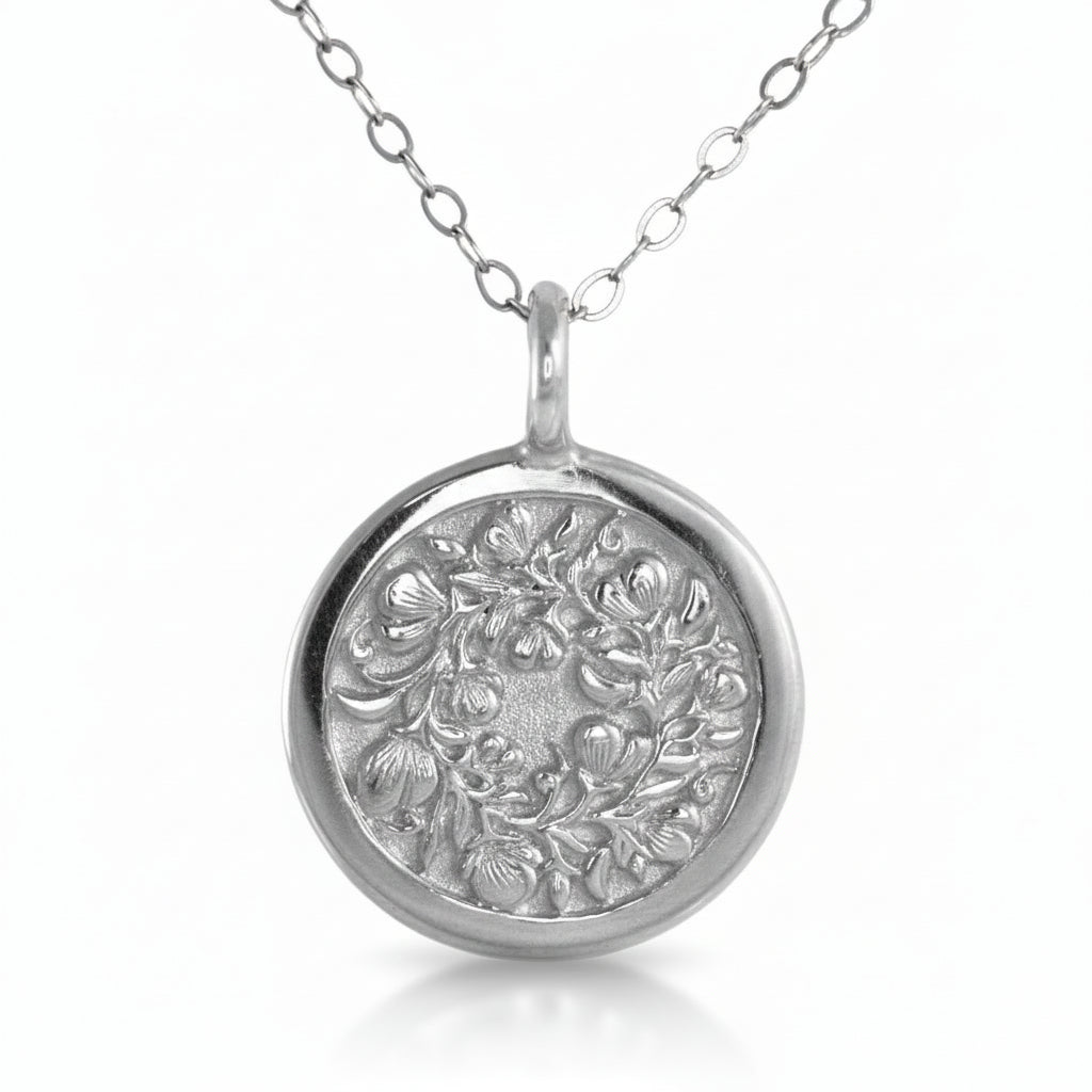 Sterling silver Sweet Pea pendant on white background – hand-engraved floral motif.