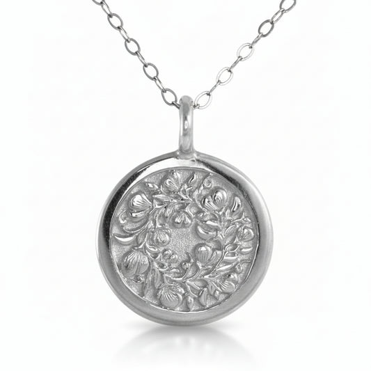 Sterling silver Sweet Pea pendant on white background – hand-engraved floral motif.
