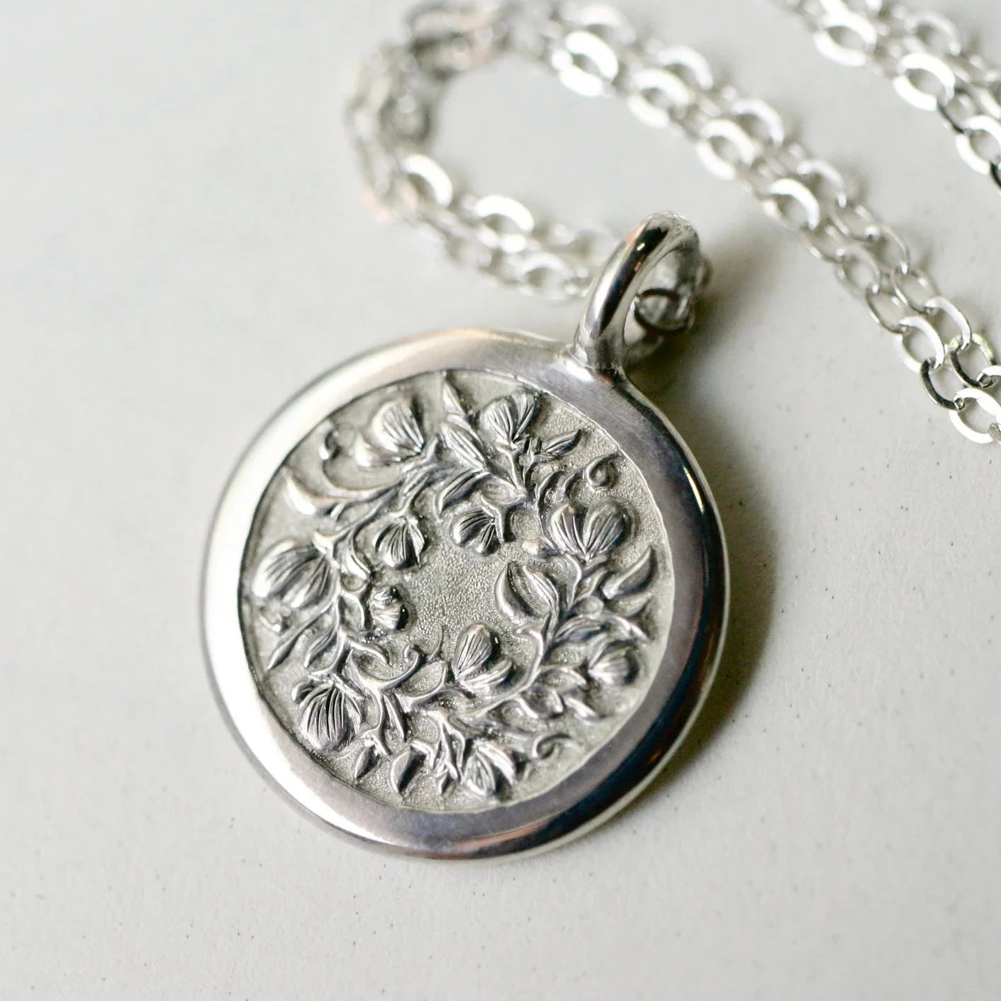 Sterling silver Sweet Pea pendant on chain – hand-engraved floral design, front view.
