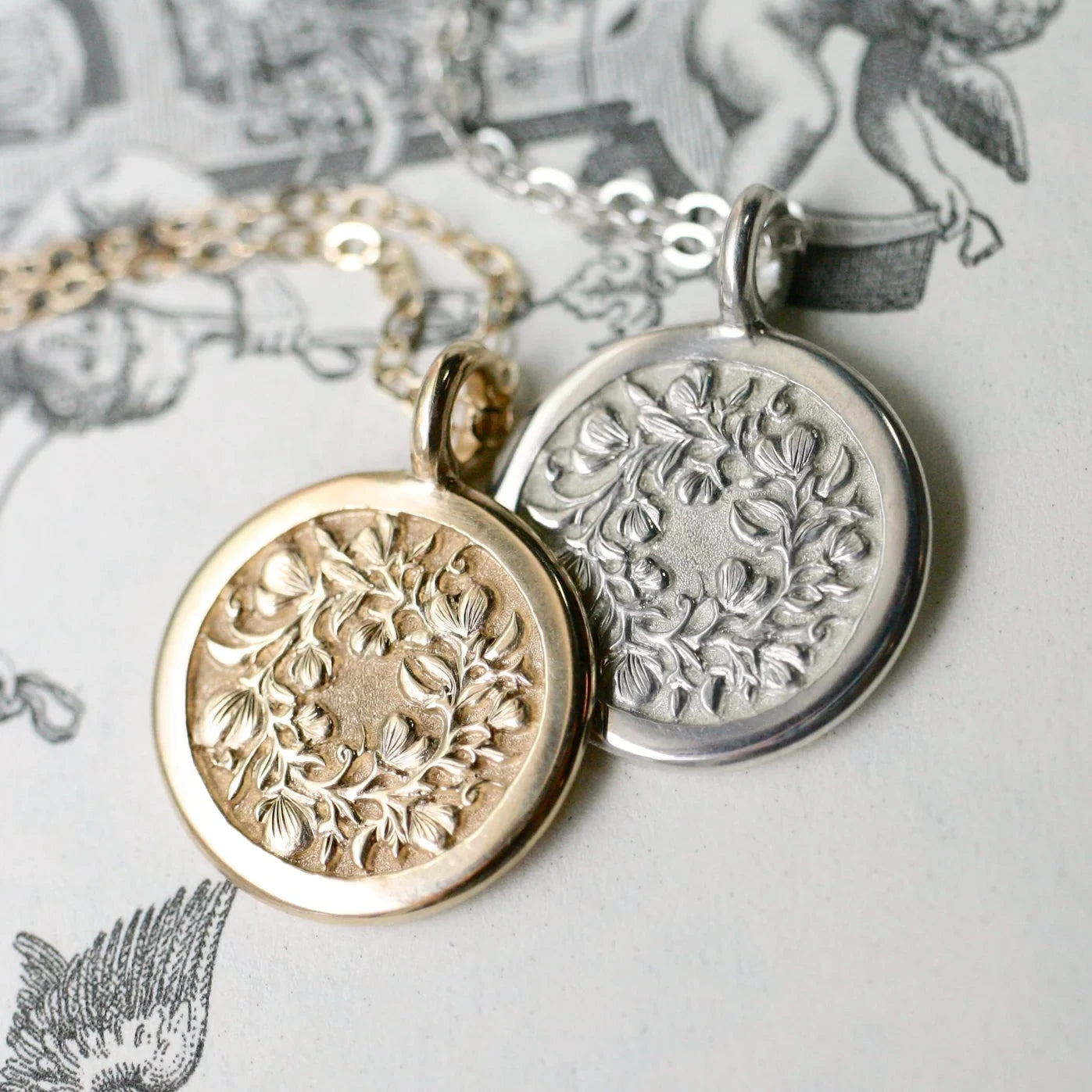 Sweet Pea pendants in sterling silver and 14k gold displayed together – engraved floral motif.