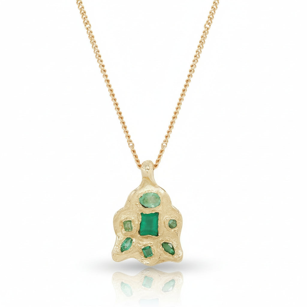 Front view of the Symplegma Emerald Pendant by Alexis Pavlantos, featuring a sculptural 14k yellow gold cluster set with natural emeralds totaling 0.40 carats, suspended from a 16-inch gold chain.