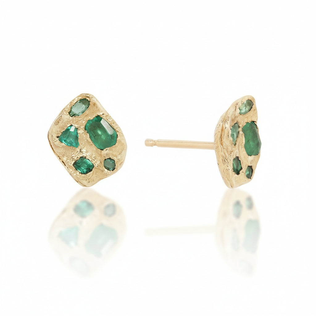 Angled view of the Symplegma Emerald Stud Earrings in solid 14k yellow gold, showcasing their organic texture, natural emerald cluster settings, and stud posts.