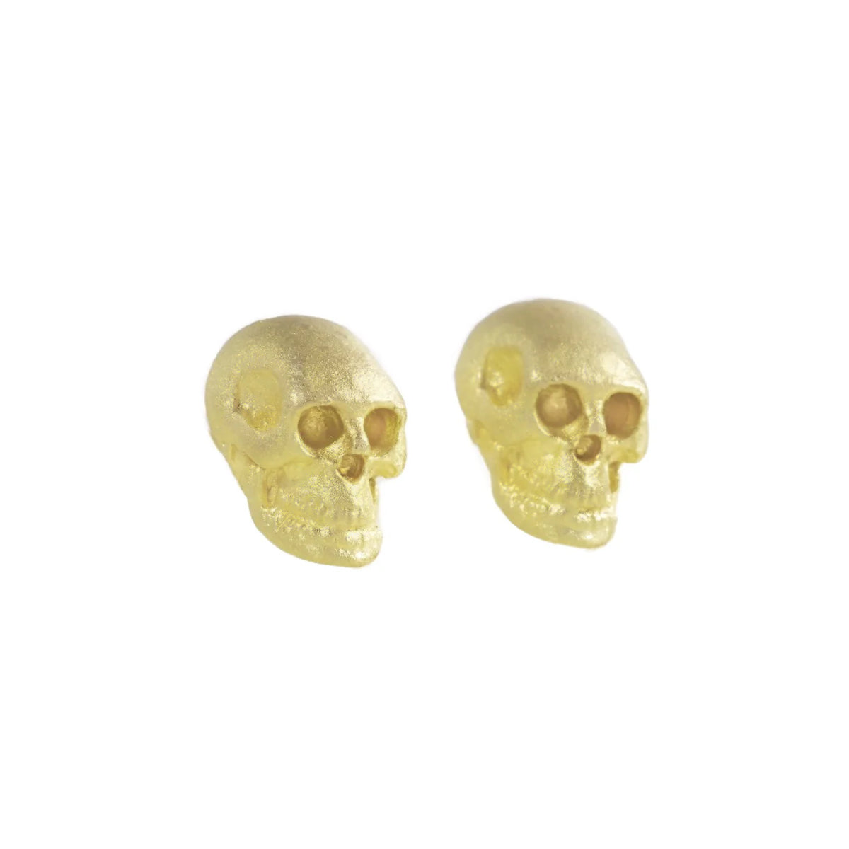 Crypta Skull Stud Earrings by Talking Tree in solid 18k yellow gold, showing the three-dimensional hand-carved skull design with gold eyes and a softly textured matte finish.