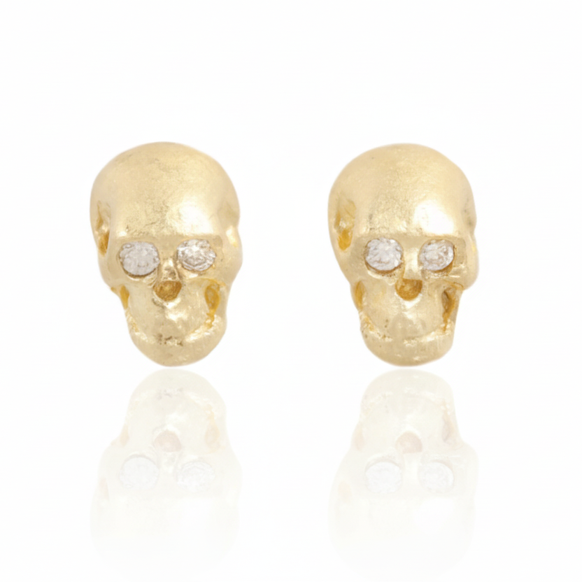 Crypta Skull Stud Earrings by Gina Pinzari of Talking Tree, featuring hand-carved solid 18k yellow gold skulls with sparkling round white diamond eyes and a soft matte finish.