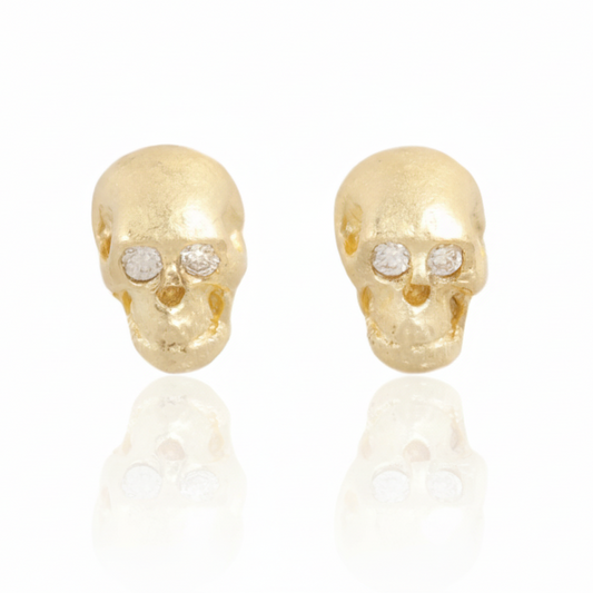 Crypta Skull Stud Earrings by Gina Pinzari of Talking Tree, featuring hand-carved solid 18k yellow gold skulls with sparkling round white diamond eyes and a soft matte finish.