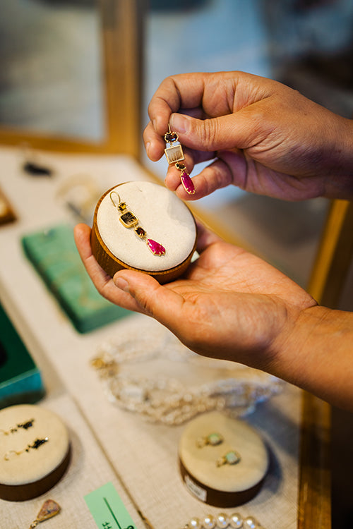 Close-up of a hand holding a jewelry display featuring handmade earrings inside Teko Gallery, an independent jewelry store in Old Town Albuquerque.