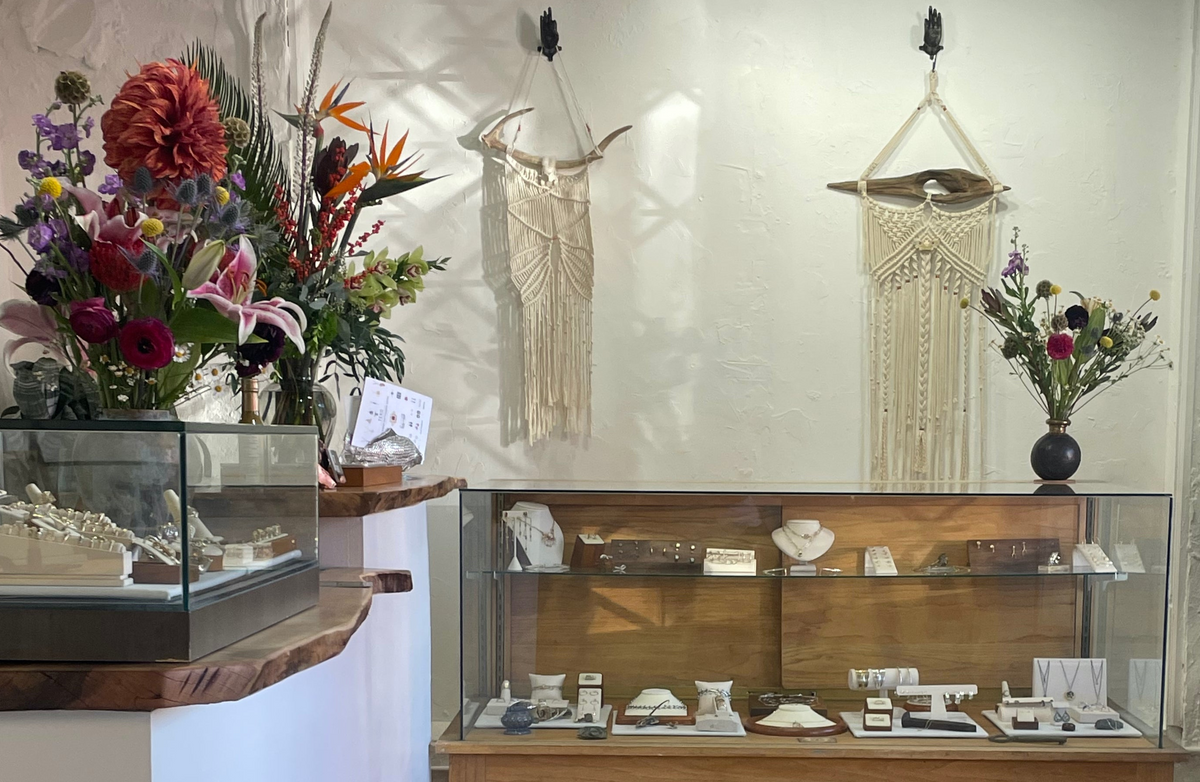 Interior of Teko Gallery in Old Town Albuquerque, featuring fine jewelry display cases, colorful floral arrangements, and handmade wall decor.