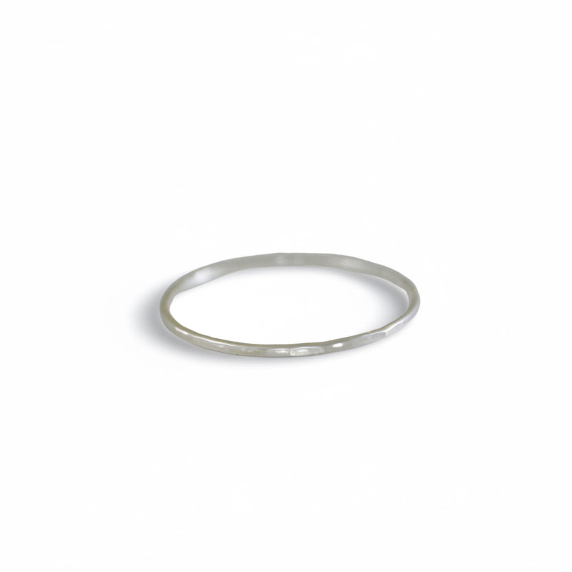 Front view of Teko Gallery's slim sterling silver stacking ring with a hand-hammered surface and polished silver finish against a white background.