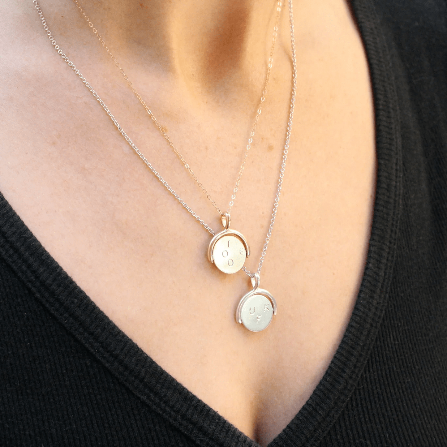 Layered gold necklaces worn on a woman’s neck, including the 14k gold thaumatrope pendant resting above the collarbone.