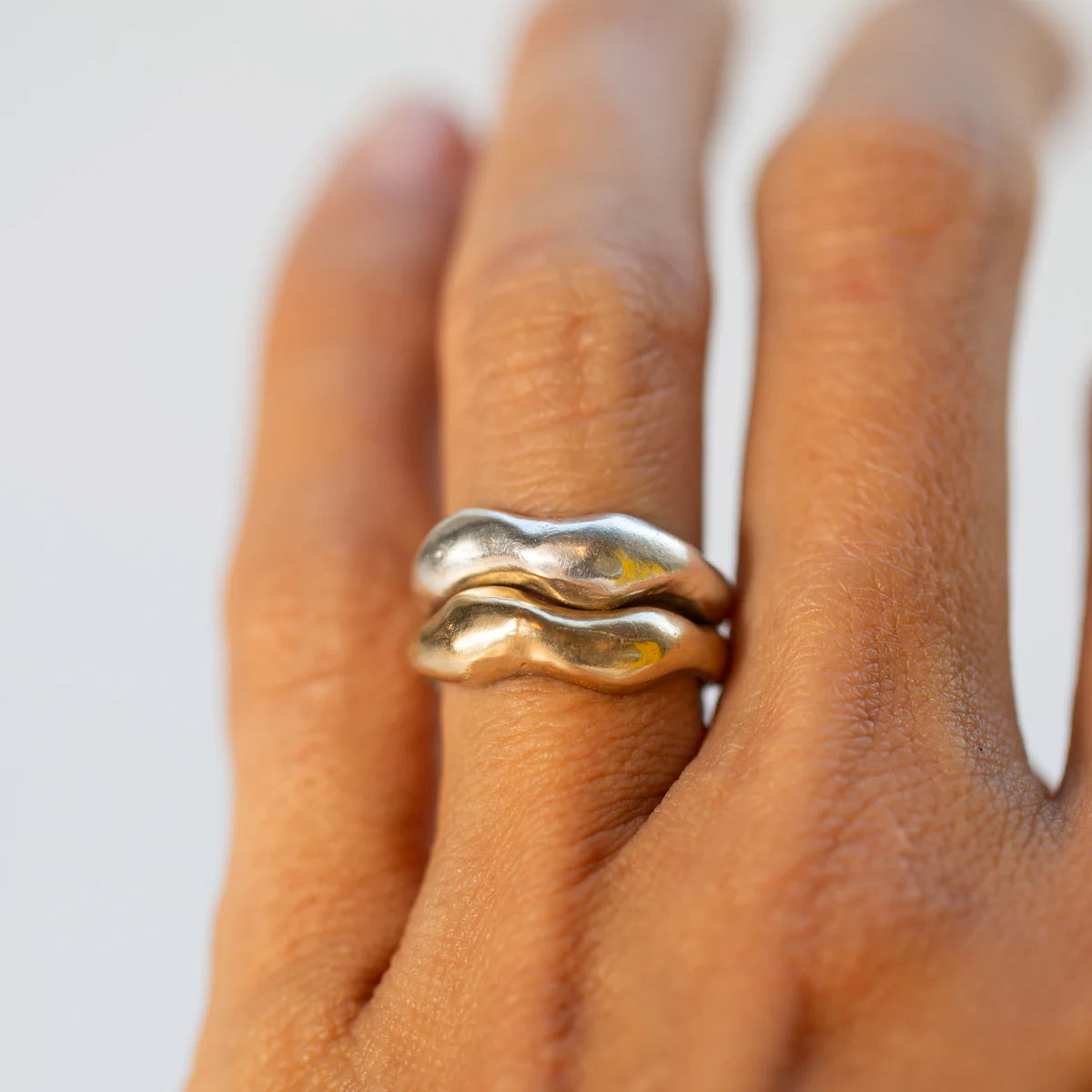 Tides Ring stack in mixed metals worn on model’s hand.