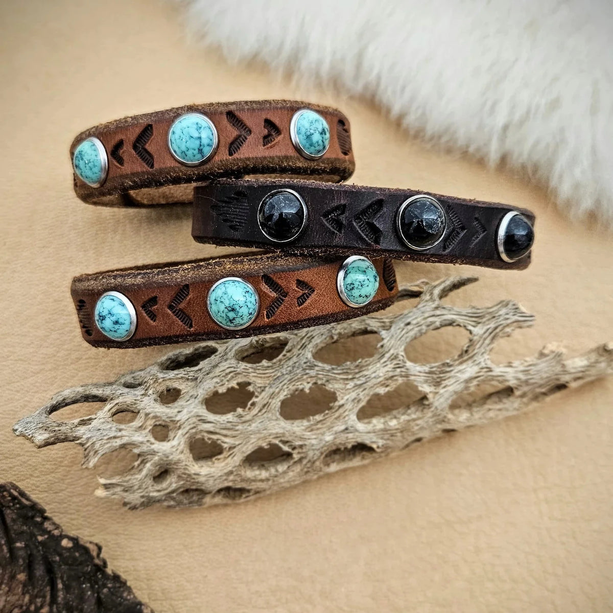 Stacked brown and black leather cuff bracelets by Kelly Horrigan featuring turquoise gemstones, silver bezels, and handcrafted leather detailing.