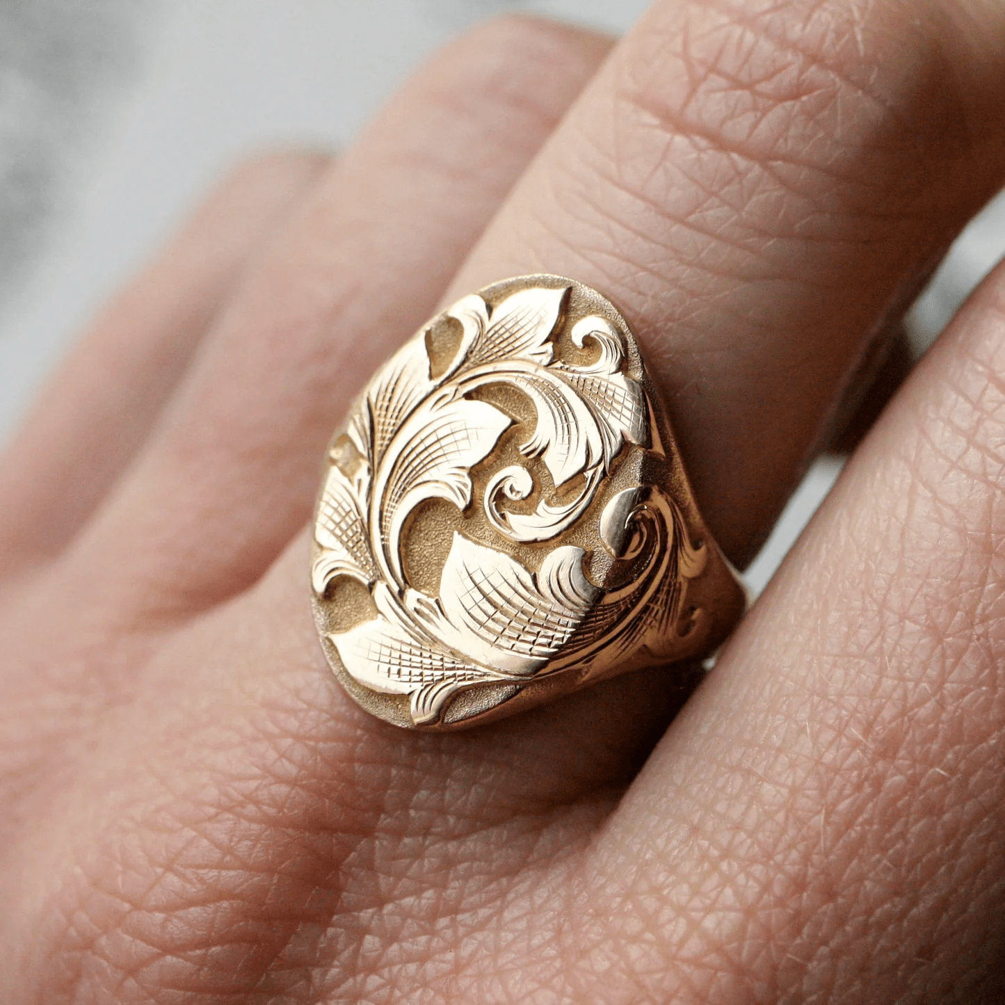 North-south acanthus signet ring worn on hand – detailed two-tone engraving