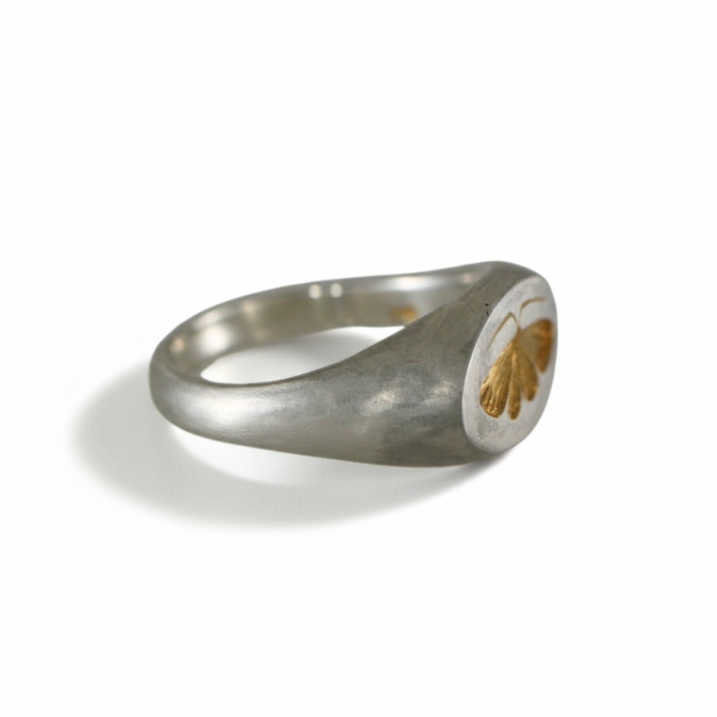 Two-tone house moth ring with a sterling silver band and gold engraved moth, shown from a side angle on a white background.