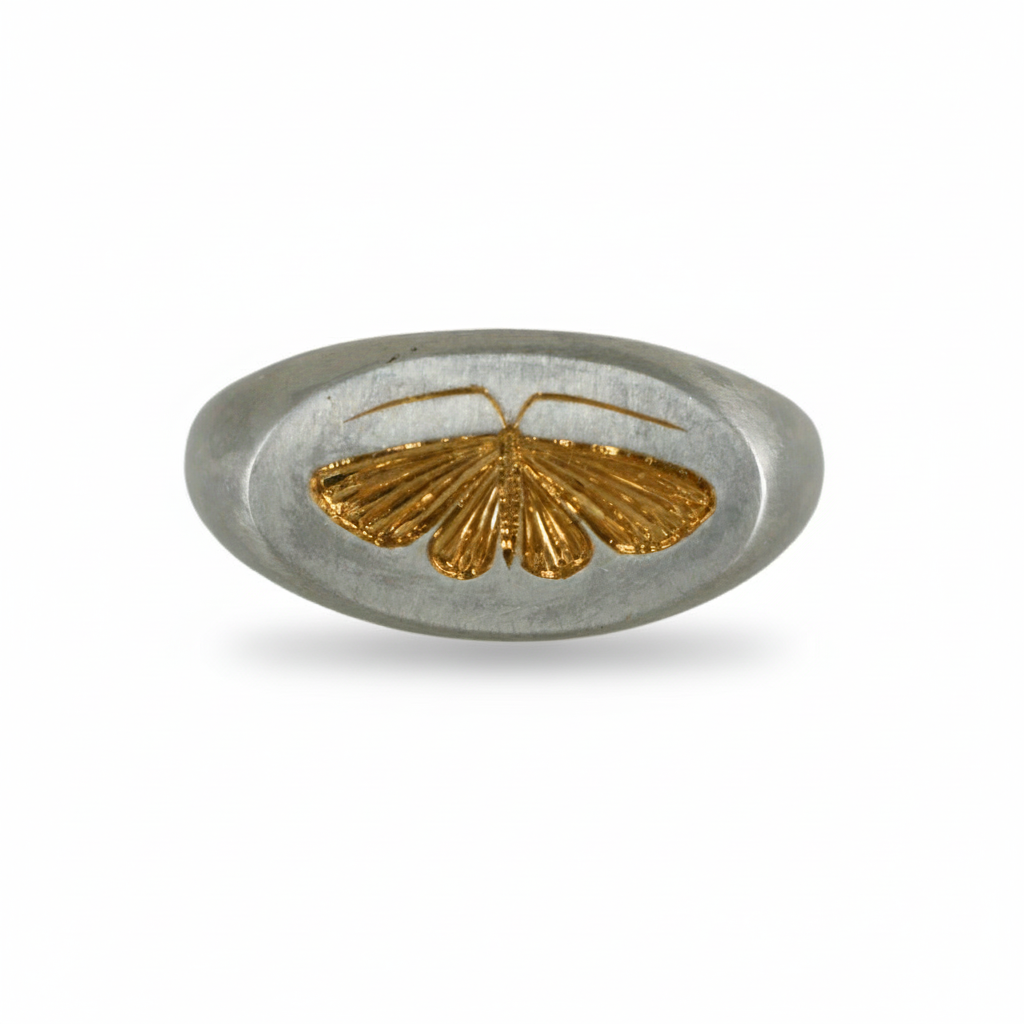 Front view of a two-tone house moth ring with a sterling silver band and gold engraved moth on a white background.