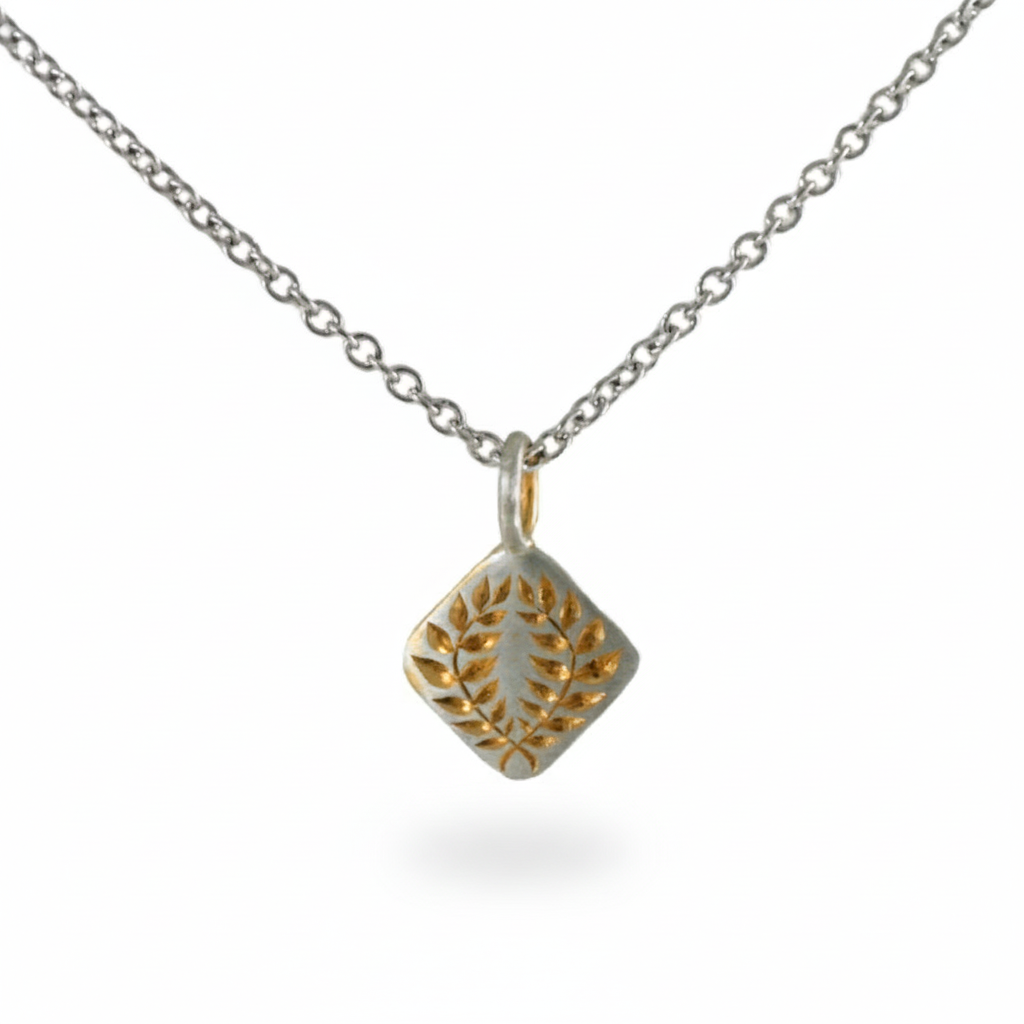 Two-tone laurel square pendant necklace with hand-engraved details on a white background.