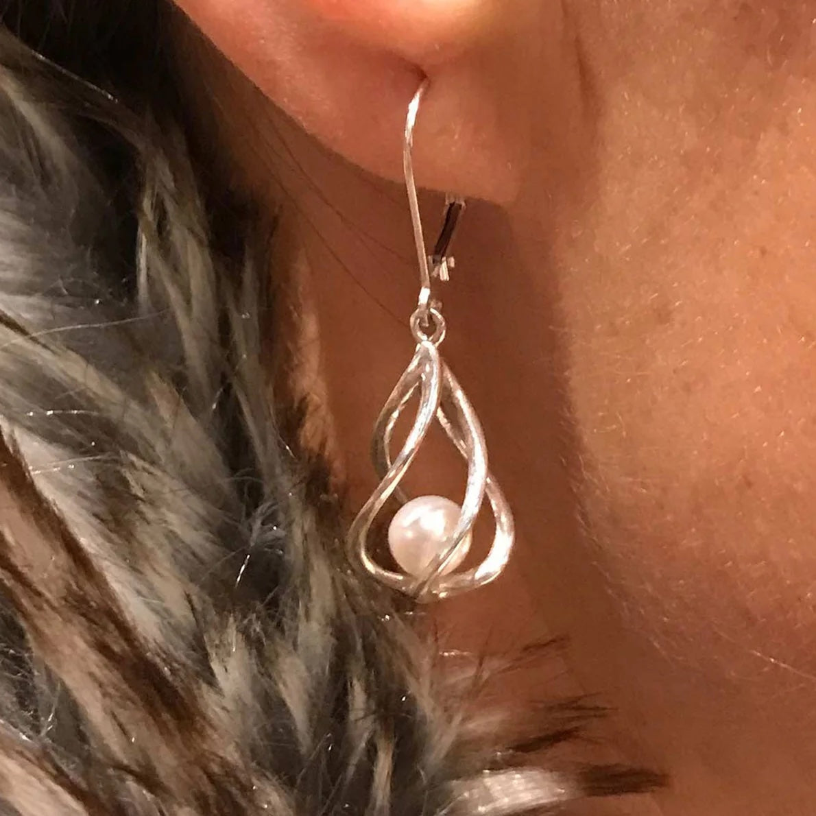 Close-up of a Vine Earring worn on the ear, featuring an open sculptural silver design and a luminous freshwater pearl.