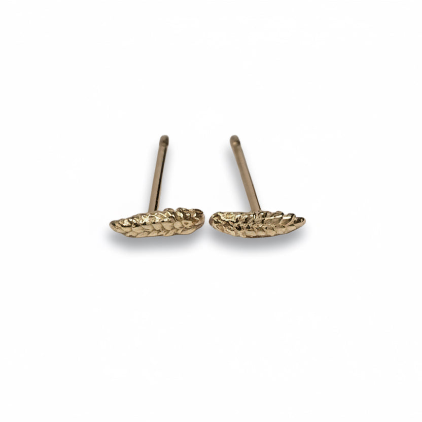 Pair of miniature wheat shaft stud earrings in 14k yellow gold, photographed at an angle to show their delicate shape and post construction.